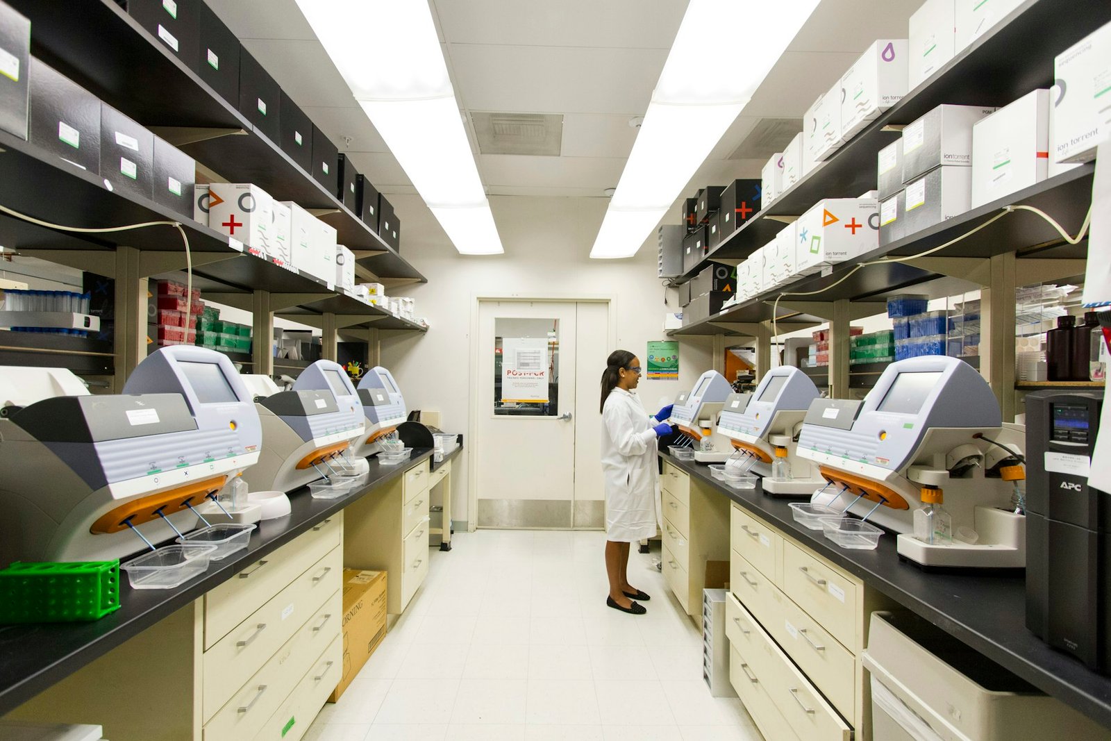 Laboratory technician working with equipment on a fully stocked laboratory bench